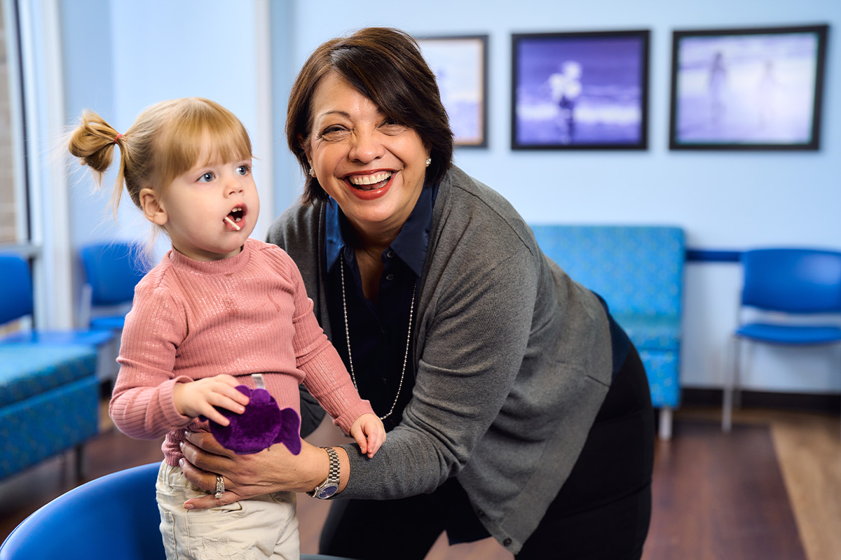A pediatric physician in Castle Hills laughing with a little girl in the waiting area