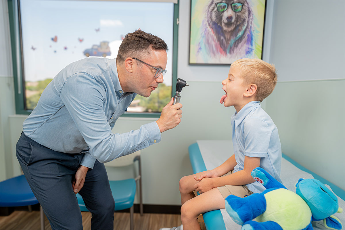 Pediatric physician examining a child&rsquo;s throat and mouth at a pediatric primary care office in Plano, Texas