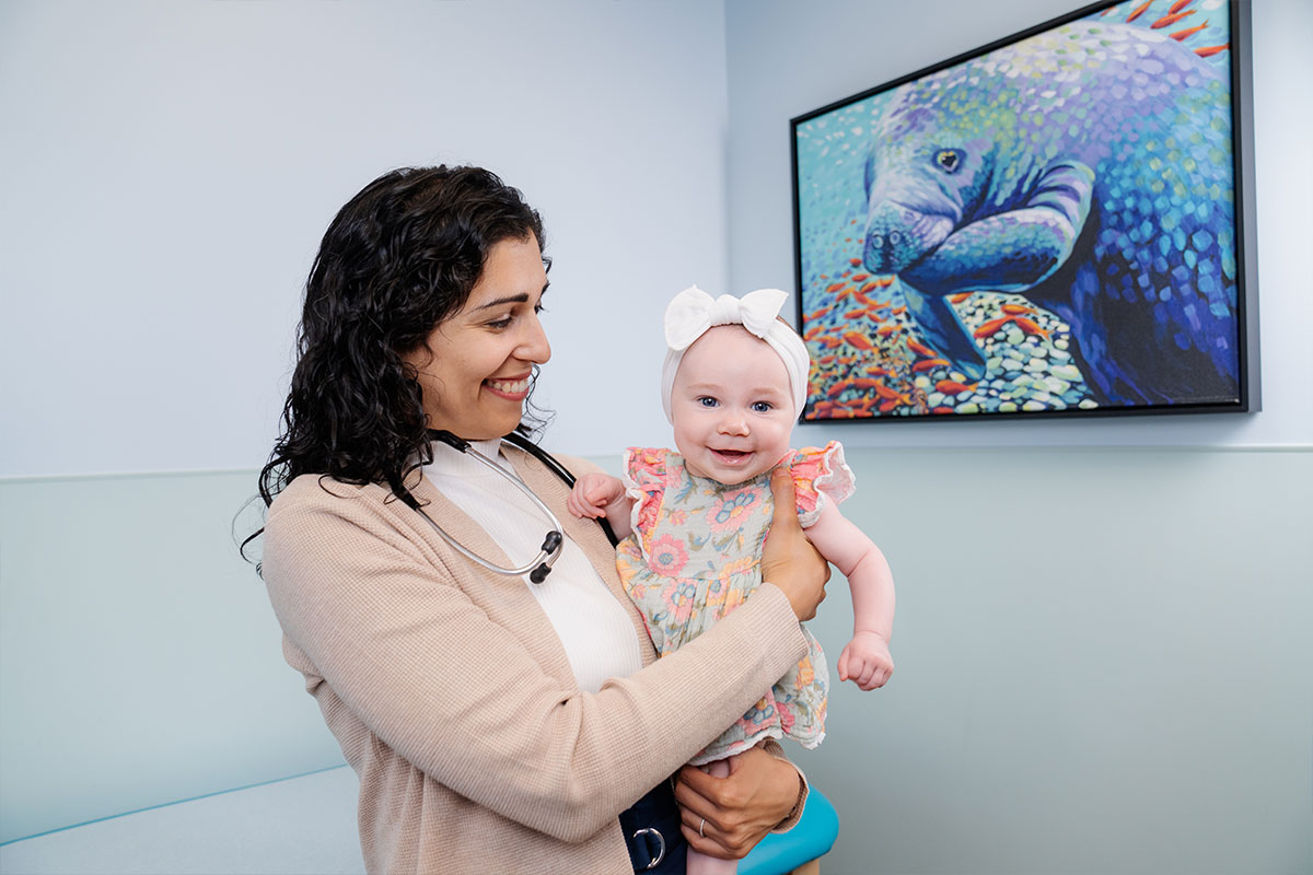 Pediatric physician holding a baby while examining the young child&rsquo;s health at a pediatric primary care office in Plano, Texas