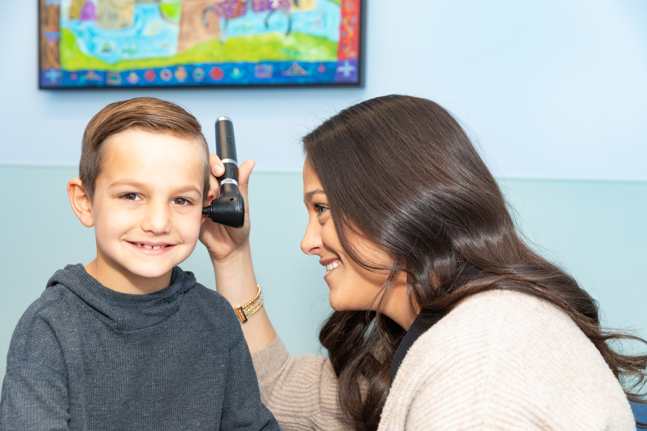 Nurse practitioner looking into boy&rsquo;s ear