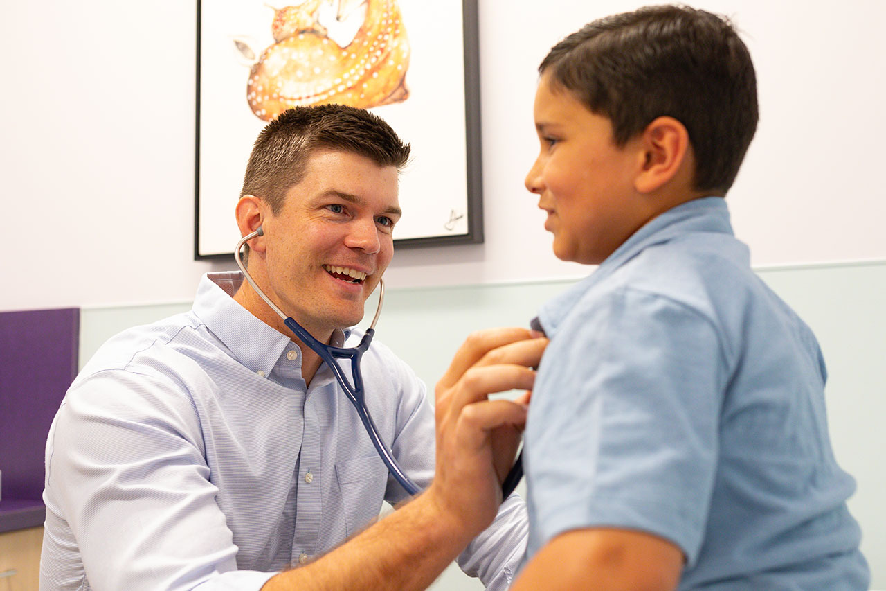 Dr. Gilmore examining a boy in blue shirt