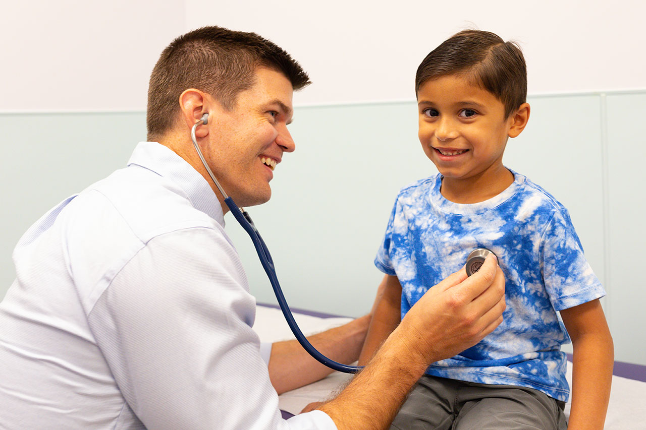 Dr. Gilmore examining boy in tie dyed shirt