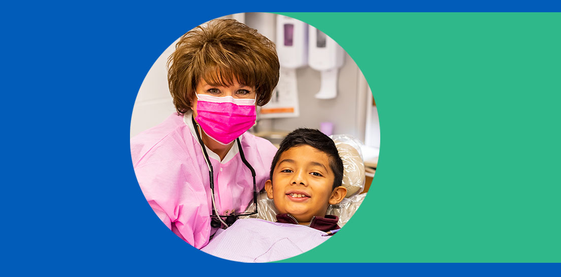 Photo of doctor in pink scrubs with a smiling boy in a dental chair in the middle of a blue and green background
