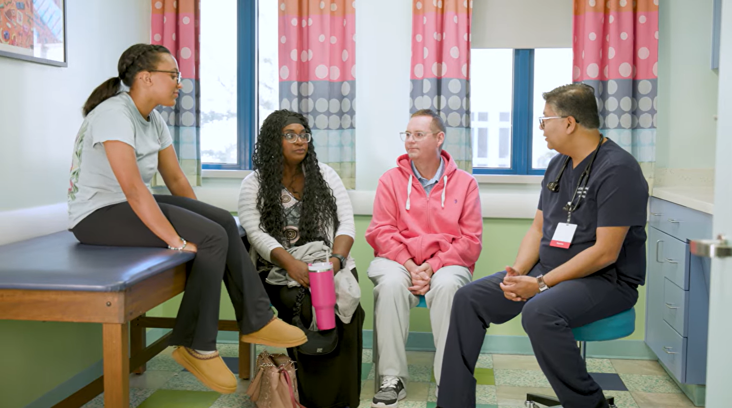 Mother, father and daughter sitting in exam room talking with doctor
