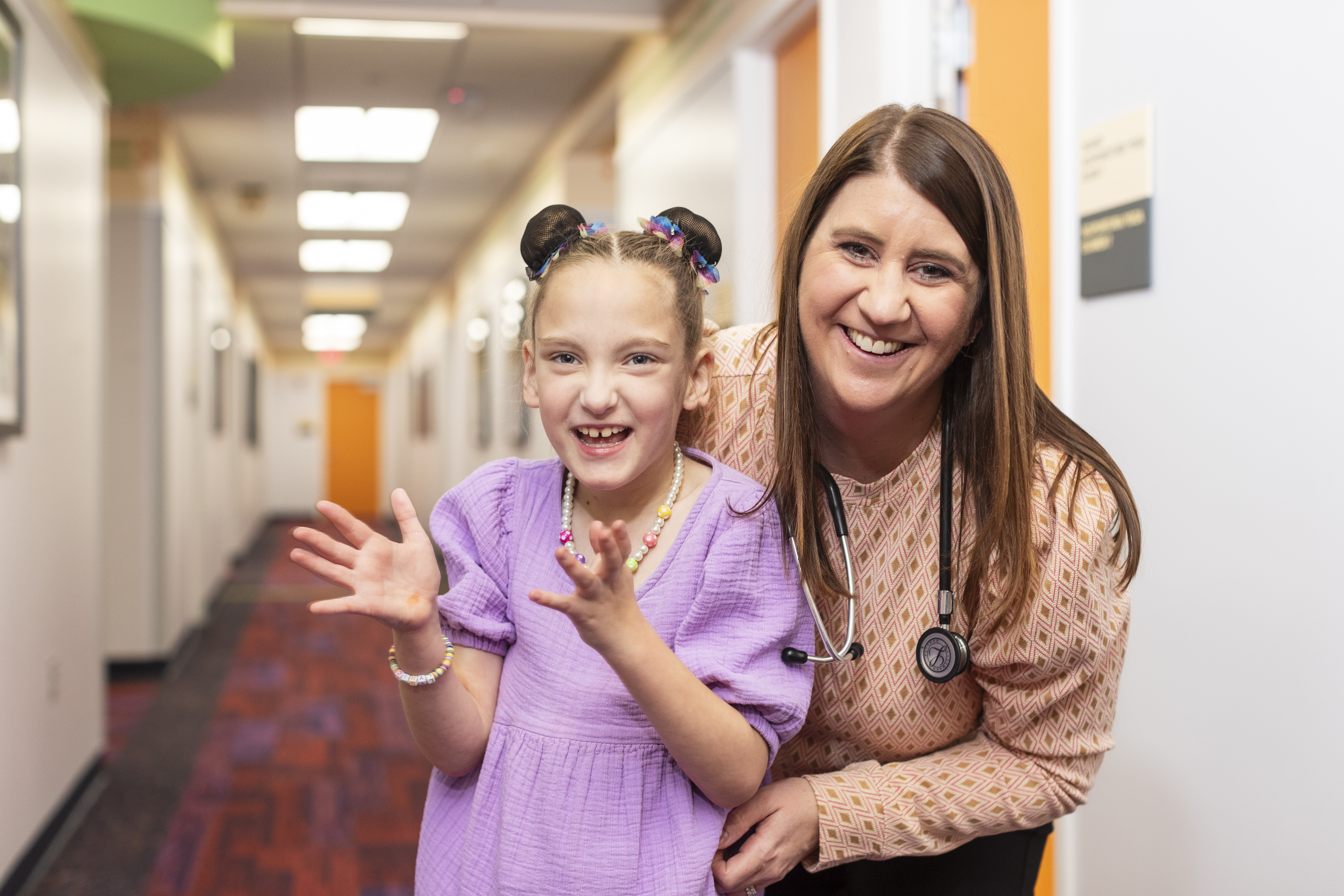 Young girl in a purple dress and doctor with a stethoscope both smiling