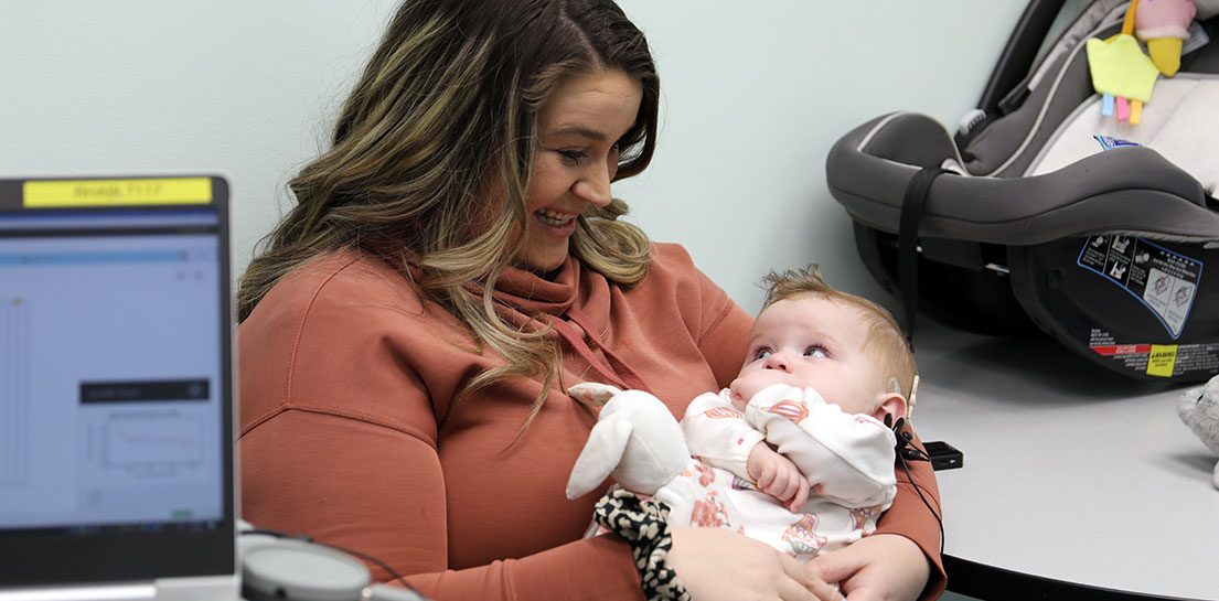 Baby with a cochlear implant being held by her mother